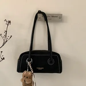 Detail of black leather underarm bag with white stitching and puppy charm
