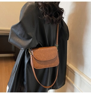 Close-up of vintage brown leather crossbody saddle bag showing fine texture and strap details