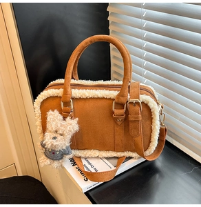Détail d'un sac Boston en daim marron avec bordure en fausse fourrure et pendentif ours