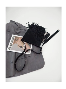 Detailed macro of black suede bucket bag featuring long fringe and silver rivet details