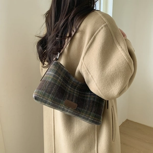 Gros plan d'un sac cabas vintage en laine à carreaux avec bandoulière en cuir et logo