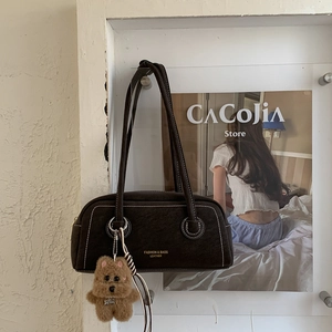 Close-up of a retro dark brown shoulder bag with contrast stitching and teddy bear charm