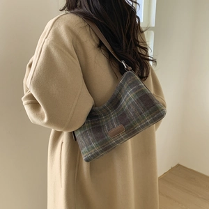 Détail du sac cabas à carreaux en laine avec écusson logo sur un manteau kaki