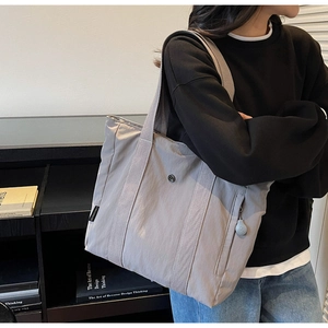 Close-up of lightweight dark grey nylon tote bag showing side zipper pocket and texture
