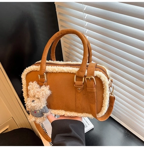 Détail d'un sac Boston en daim marron avec garniture en peluche et pendentif ours mignon