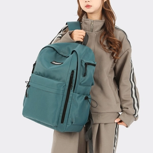 Detail view of teal travel backpack showing multiple zipper pockets and side drawstrings