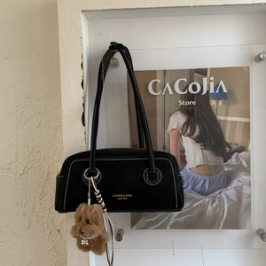 Detail of black suede shoulder bag with contrast stitching and bear charm