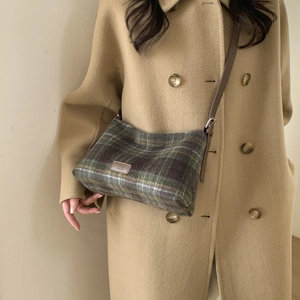 Détail d'un cabas en laine à carreaux avec étiquette cuir et manteau d'automne