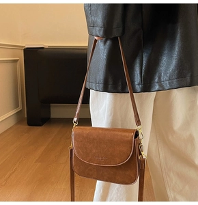 Detail of vintage brown leather bag showing adjustable strap and gold metal hardware