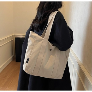 Close-up of minimalist cream tote bag with nylon texture and black brand logo patch