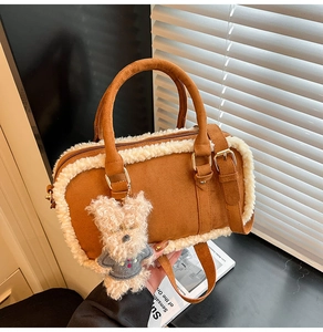 Détail du sac Boston en daim marron avec bordure en peau de mouton et charmant ours peluche