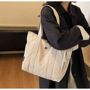 Detail of off-white canvas tote bag featuring black woven label and side view on model
