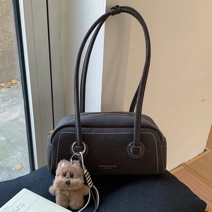 Detail of vintage textured leather Boston bag with contrast stitching and bear charm