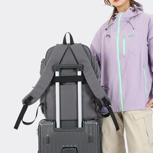 Detail of grey travel backpack with a luggage strap secured on a suitcase handle