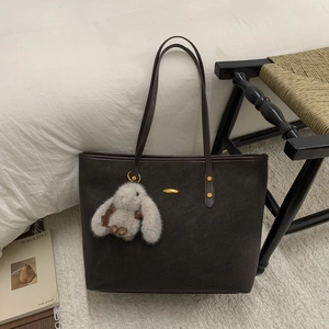 Détail du grand sac cabas en daim marron foncé avec boucle dorée et breloque lapin en peluche