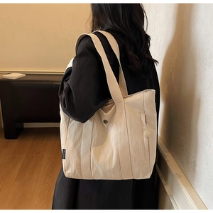 Detail of light beige tote bag featuring a front snap pocket and durable nylon texture