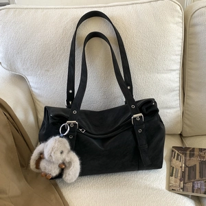 Detail of black matte leather tote bag with silver studs and a plush bunny charm