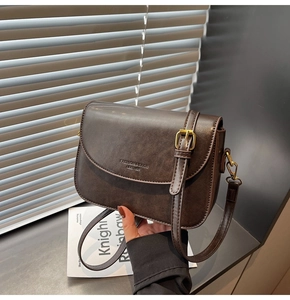 Detail of vintage dark brown faux leather bag with embossed logo and gold buckle