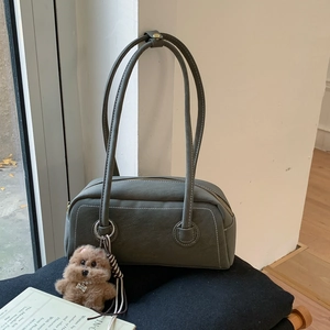 Close-up of retro gray-green underarm bag with white stitching and plush dog charm