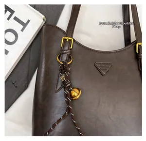Close-up of coffee brown matte leather tote with braided rope and metallic bell detail