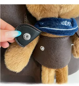 Nahaufnahme von Plüschbär-Anhänger mit blauem Schal und Lederweste an einer Tasche