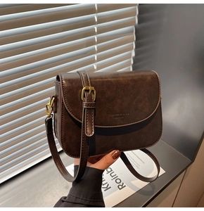 Detail of dark brown vintage leather crossbody bag with gold hardware and embossed text