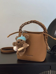 Brown lychee leather bucket bag with braided handle and cute plush bear charm accessory