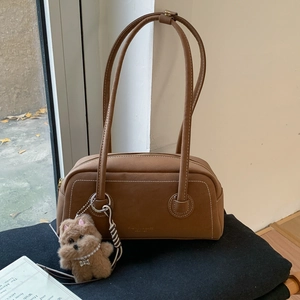 Detail shot of brown retro shoulder bag with white stitching and plush dog charm