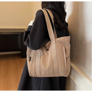 Minimalist apricot tote bag detail featuring side zipper pocket and metal snap closure