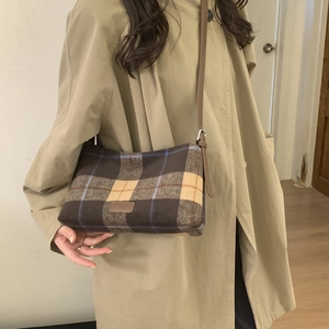 Détail du sac cabas à carreaux en laine avec bandoulière en cuir brun et texture vintage