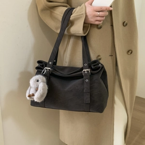 Detail of dark grey frosted shoulder bag with silver eyelets and plush bird charm