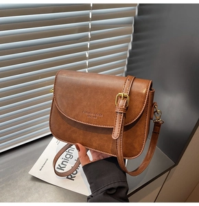 Detail of vintage brown shoulder bag with golden buckle and fine lychee grain leather texture