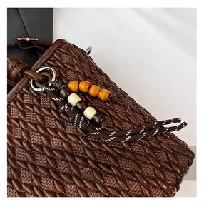 Detailed macro of dark brown woven handbag featuring wooden beads and tassel accents