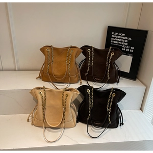Quilted tote bags with chain straps in brown, beige, and black displayed on steps