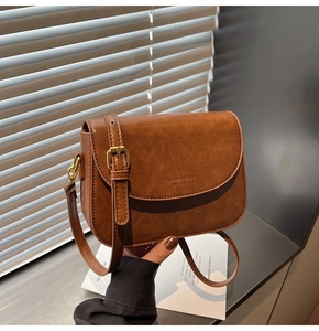Detail of caramel faux leather bag featuring elegant gold buckles and embossed text
