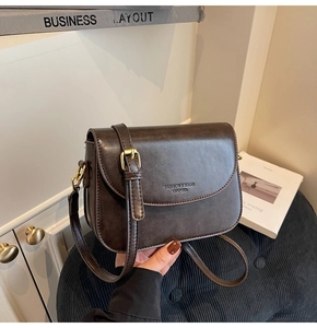 Detail of vintage brown leather saddle bag featuring gold hardware and logo engraving