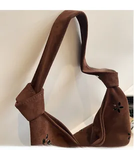 Detail of dark brown suede tote bag featuring a stylish knotted shoulder strap and laser-cut floral patterns