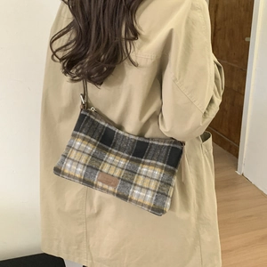 Détail d'un sac cabas vintage à carreaux en laine avec écusson en cuir tendance