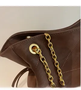 Close-up of vintage brown suede tote featuring gold chunky chain strap and metal eyelets