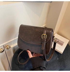 Detail of vintage brown leather handbag with embossed fashion logo on soft corduroy
