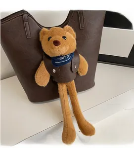 Detail eines süßen Teddybär-Anhängers mit blauem Schal an einer braunen Ledertasche