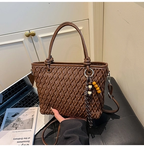 Detailed texture of dark brown woven bucket bag with wooden bead pendant and slim strap