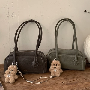 Close-up of matte leather tote bags with contrast stitching and teddy bear charms