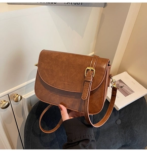 Close-up of brown vintage crossbody bag with leather texture and gold buckle detail