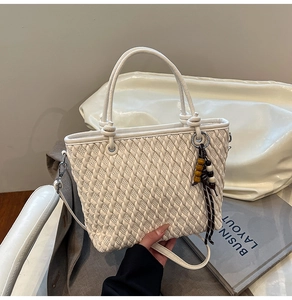 Detail of white woven bucket bag with beaded tassel and detachable shoulder strap