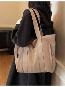Minimalist khaki nylon tote bag with wide straps and external zipper shown on model