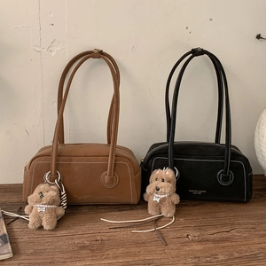 Detail view of vintage leather hobo bags in brown and black with plush dog charms