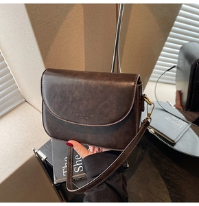 Detail of dark brown leather handbag with gold metal hardware and fashion text