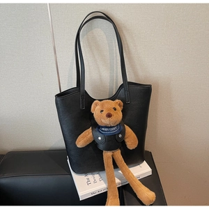 Detail einer schwarzen Leder-Eimertasche mit niedlichem braunem Plüschbär-Anhänger