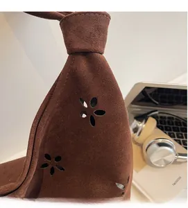 Detailed close-up of dark brown suede bag featuring unique floral cutout side patterns